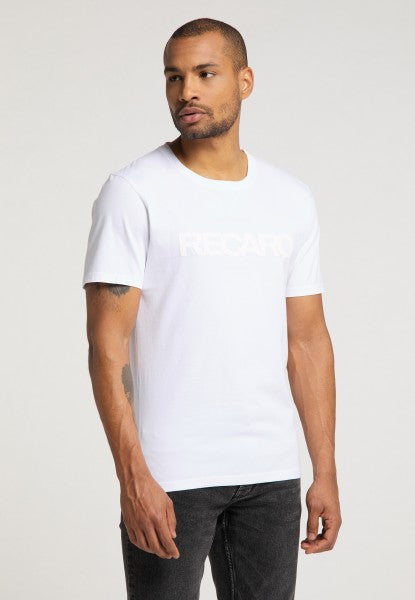 Ein Mann trägt ein T-Shirt Originals RECARO mit hellem Schriftzug, dazu eine schwarze Jeans und steht vor einem schlichten hellen Hintergrund.