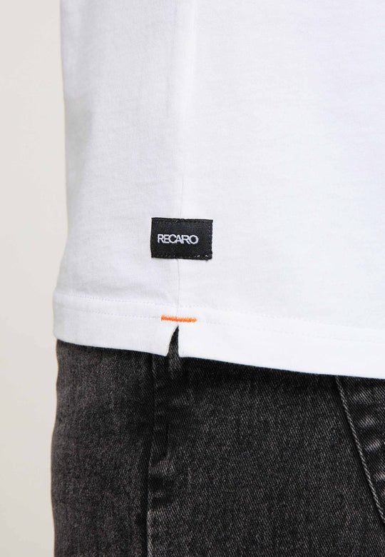 Nahaufnahme eines weißen T-Shirts Spektrum von Recaro mit kleinem schwarzen Etikett am Saum, kombiniert mit dunkler Jeans. Der Fokus liegt auf dem Etikett und dem Saum und verleiht dem Outfit einen dezenten Retro-Look.
