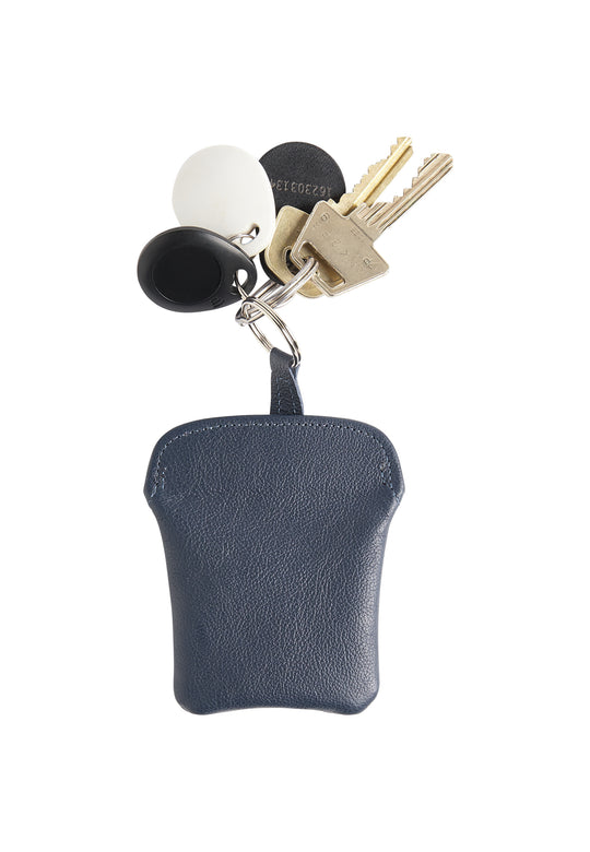 Ein Schlüsselsatz an einem Schlüsselring mit einem kleinen marineblauen Recaro_Merch_Daniel Leder-Schlüsselmäppchen, einem schwarzen runden Token, einem weißen runden Token und zwei daran befestigten goldenen Schlüsseln.