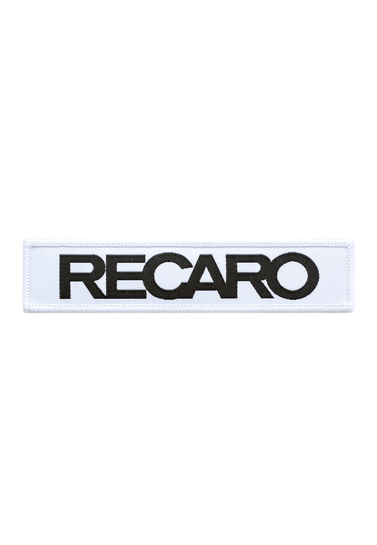 Der Patch RECARO 110x25mm von RECARO ist ein rechteckiger weißer Patch aus strapazierfähigem Material, auf dem mittig das Wort RECARO in fetten schwarzen Großbuchstaben abgebildet ist.
