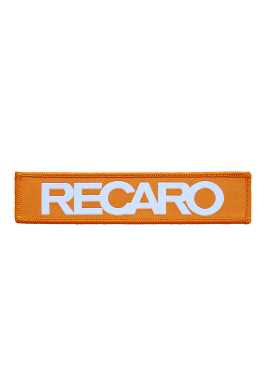Der Patch RECARO 110x25mm von RECARO ist ein langlebiger orangefarbener rechteckiger Patch mit fettem weißen „RECARO“-Schriftzug.