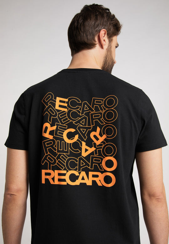 Ein Mann trägt mit dem Rücken zur Kamera das Recaro_Merch_Daniel T-Shirt Backprint – ein schwarzes Baumwoll-T-Shirt mit mehreren orange-gelben RECARO-Logos im Farbverlauf auf der Rückseite.