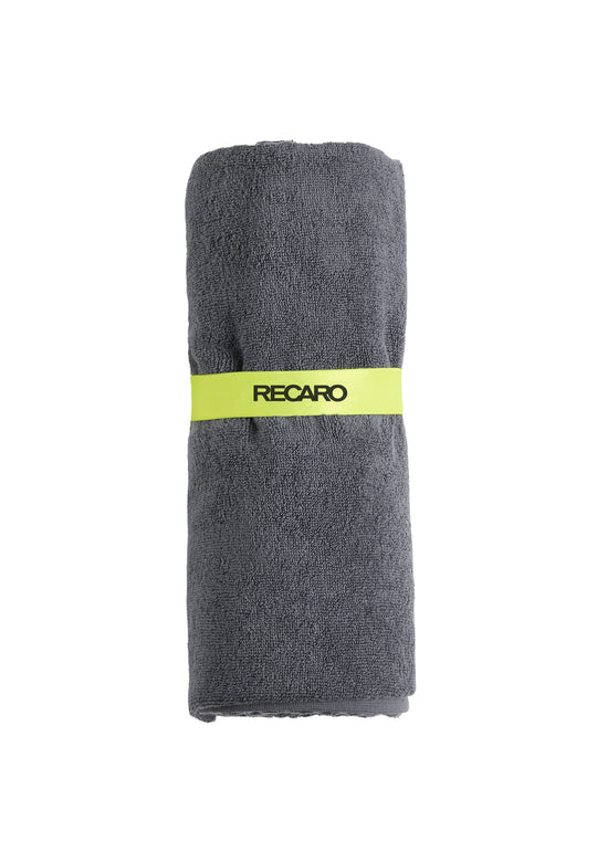 Das extra große, dunkelgraue Fitness- und Freizeithandtuch Performance von RECARO aus Baumwoll-Zwirnfrottee ist zusammengerollt und mit einem hellgelben Band samt schwarzem Recaro-Schriftzug gesichert.