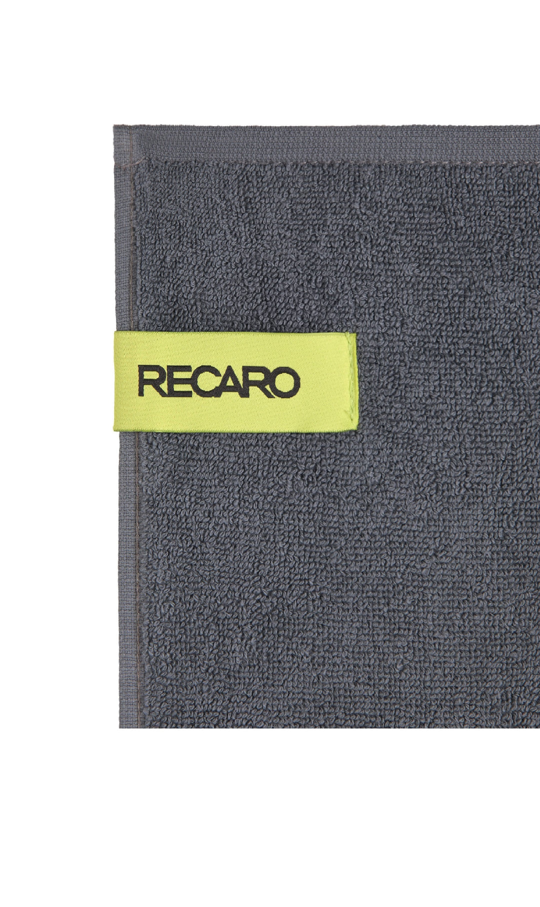 Eine Nahaufnahme eines dunkelgrauen Fitness- und Freizeithandtuchs Performance von RECARO aus hochwertigem Baumwoll-Twill-Frottee mit einer gelbgrünen Stoffschlaufe mit „RECARO“ in schwarzen Buchstaben.
