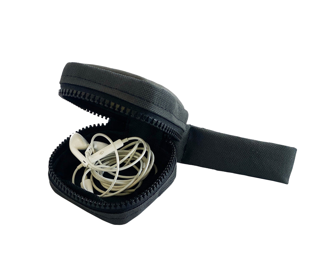 Ein kleines schwarzes Etui mit Reißverschluss ist geöffnet und gibt den Blick auf ein Paar weiße, kabelgebundene Ohrhörer frei, die ordentlich darin aufgerollt sind. Das Etui hat eine Stofflasche und ist vor einem weißen Hintergrund angebracht.