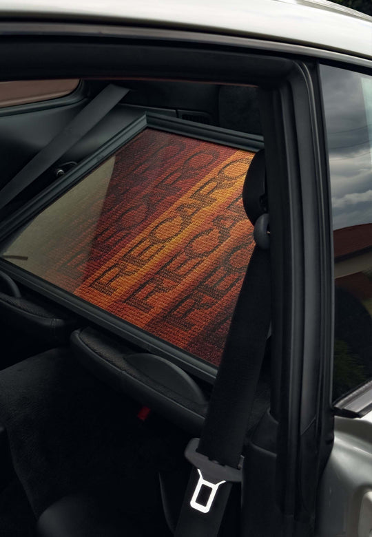 Ein RECARO Shop Poster Spektrum 50 x 70cm in leuchtenden Orange- und Rottönen, made in Germany, steht auf der Rückbank eines Autos, an den Sitz gelehnt und durch die offene Tür sichtbar.
