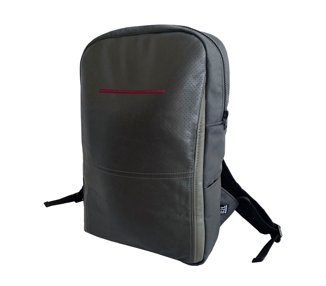 Ein eleganter, dunkelgrauer Rucksack mit minimalistischem Design, einer einzelnen dünnen roten Akzentlinie auf der Vorderseite und verstellbaren schwarzen Schultergurten vor einem weißen Hintergrund.