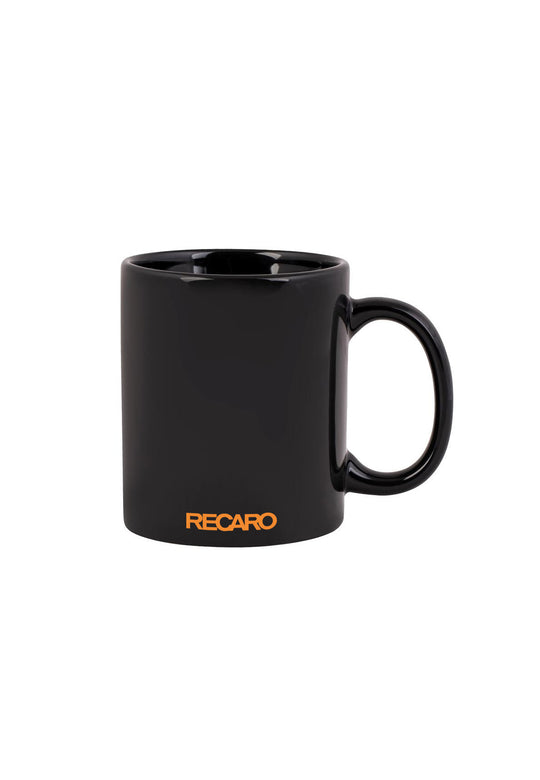 Die RECARO_Merchandising Tasse Spektrum, eine schlichte schwarze Keramiktasse mit dem orangefarbenen Schriftzug „RECARO“ am Boden, gestaltet von Spektrum Design, ist auf weißem Untergrund abgebildet.