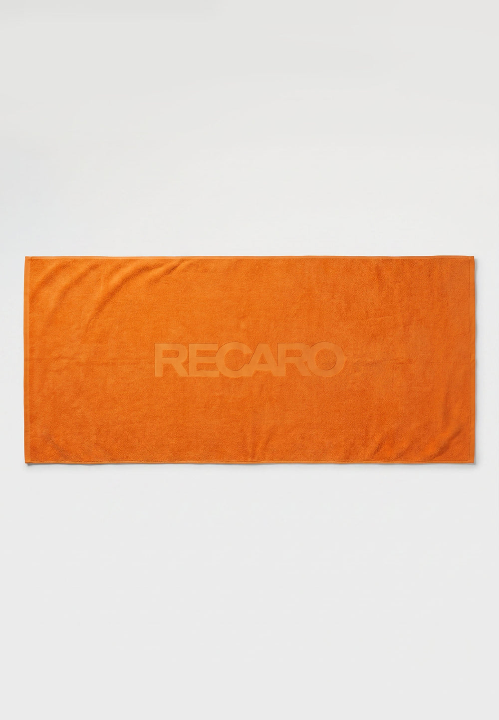 Ein orangefarbenes, rechteckiges RECARO XXL-Handtuch aus dem RECARO-Shop, das zu 100 % aus Baumwolle besteht und in dessen Mitte der Schriftzug „RECARO“ dezent eingeprägt ist, liegt flach auf einem weißen Hintergrund.