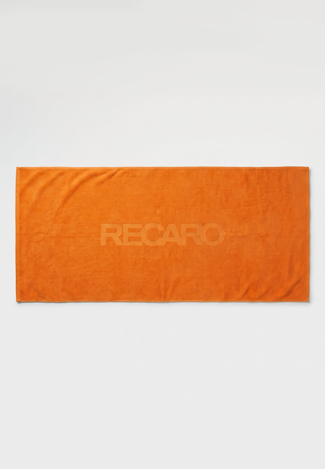 Ein orangefarbenes, rechteckiges RECARO XXL-Handtuch aus dem RECARO-Shop, das zu 100 % aus Baumwolle besteht und in dessen Mitte der Schriftzug „RECARO“ dezent eingeprägt ist, liegt flach auf einem weißen Hintergrund.