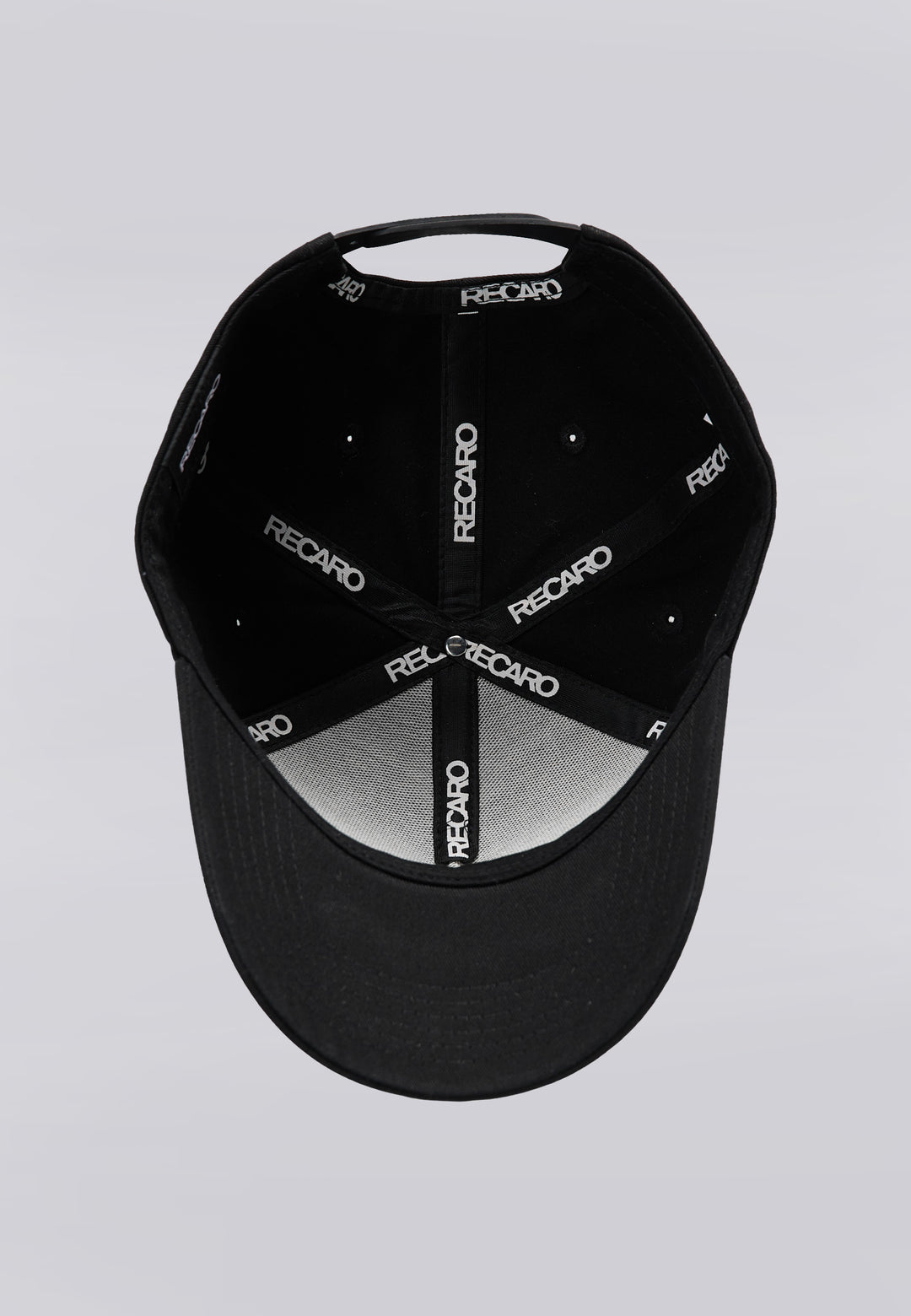 Eine schwarze Recaro_Merch_Daniel Baseballkappe der Serie „Originals“ wird von oben gezeigt, sodass die Innenseite zu sehen ist. Die Innennähte sind mit schwarzen Stoffstreifen versehen, auf denen das weiße Recaro_Merch_Daniel-Logo zu sehen ist. Eine markante 3D-Stickerei verleiht dem Logo zusätzliche Tiefe, und der Druckknopfverschluss der Kappe sorgt für eine individuell anpassbare Passform. Unten ist der Schirm der Kappe zu sehen.