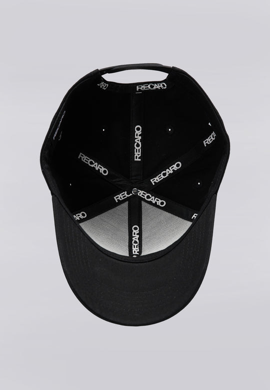 Eine schwarze Recaro_Merch_Daniel Baseballkappe der Serie „Originals“ wird von oben gezeigt, sodass die Innenseite zu sehen ist. Die Innennähte sind mit schwarzen Stoffstreifen versehen, auf denen das weiße Recaro_Merch_Daniel-Logo zu sehen ist. Eine markante 3D-Stickerei verleiht dem Logo zusätzliche Tiefe, und der Druckknopfverschluss der Kappe sorgt für eine individuell anpassbare Passform. Unten ist der Schirm der Kappe zu sehen.