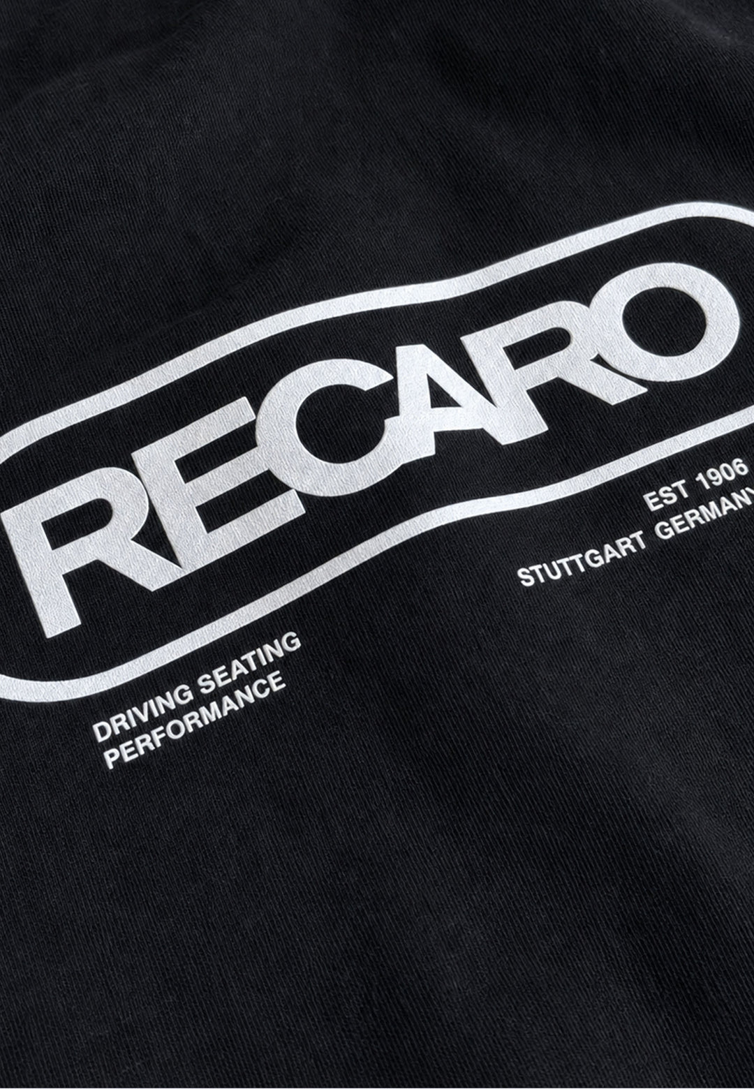 Diese aus schwarzem Stoff gefertigte Hoodiejacke „Retro Backprint“ von RECARO Shop ist mit dem ikonischen weißen RECARO-Logo versehen. Unterhalb des Logos sind die Aufschriften „DRIVING SEATING PERFORMANCE“, „EST 1906“ und „STUTTGART GERMANY“ aufgedruckt, die die pure Rennsport-DNA widerspiegeln und die Tradition sowie den Stil zelebrieren, für die echte Motorsportbekleidung steht – genau wie die legendäre RECARO Retro-Hoodiejacke.
