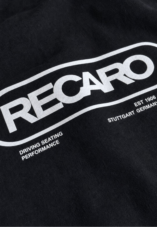 Diese aus schwarzem Stoff gefertigte Hoodiejacke „Retro Backprint“ von RECARO Shop ist mit dem ikonischen weißen RECARO-Logo versehen. Unterhalb des Logos sind die Aufschriften „DRIVING SEATING PERFORMANCE“, „EST 1906“ und „STUTTGART GERMANY“ aufgedruckt, die die pure Rennsport-DNA widerspiegeln und die Tradition sowie den Stil zelebrieren, für die echte Motorsportbekleidung steht – genau wie die legendäre RECARO Retro-Hoodiejacke.