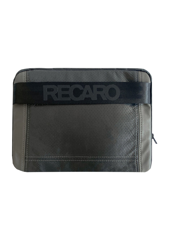 Die Tech & Travel Laptoptasche aus dem RECARO Shop ist eine rechteckige, graue Tasche aus RECARO-Sitzleder mit sichtbaren Nähten, einem schwarzen Riemen mit prägnantem RECARO-Schriftzug und einem Reißverschluss auf der rechten Seite. Teil der exklusiven Upcycling-Kollektion.