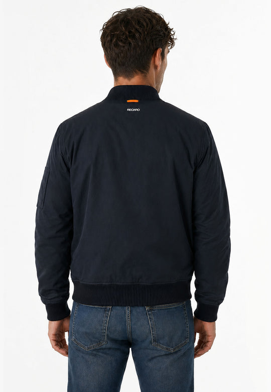 Ein Mann mit kurzen, lockigen braunen Haaren ist von hinten zu sehen. Er trägt die wind- und wasserabweisende Pilotenjacke RECARO in navy von RECARO Shop und blaue Jeans. Die Jacke hat ein kleines Logo am oberen Rücken auf weißem Grund.