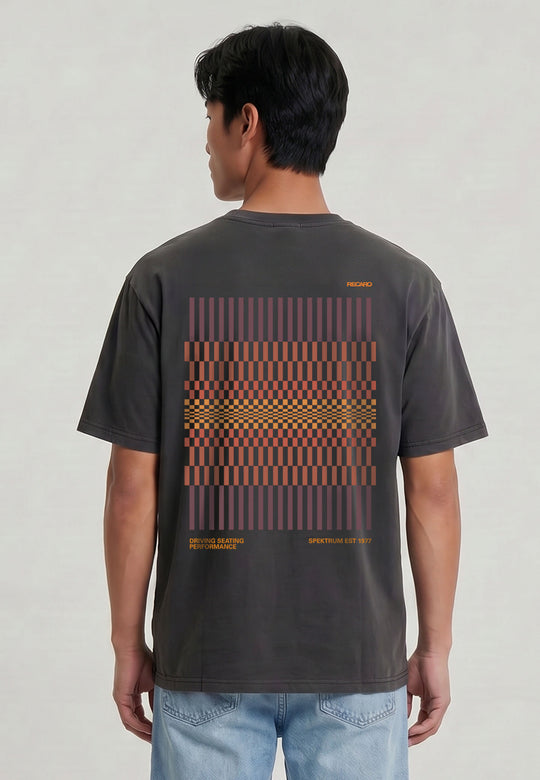 Vor einem hellen, unifarbenen Hintergrund steht eine Person, die das RECARO Shop T-Shirt Spektrum Backprint, Garment Washed, mit einem orange-roten, geometrischen Muster und kleinem Text auf dem Rücken trägt.