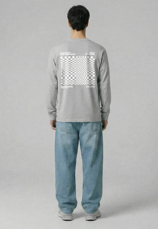Eine Person blickt von sich weg und trägt das RECARO Shop Longsleeve Checkered in Hellgrau mit einem auffälligen weißen Schachbrettmuster und RECARO Logo auf dem Rücken, gepaart mit lockeren hellblauen Jeans und weißen Turnschuhen vor einem grauen Hintergrund.